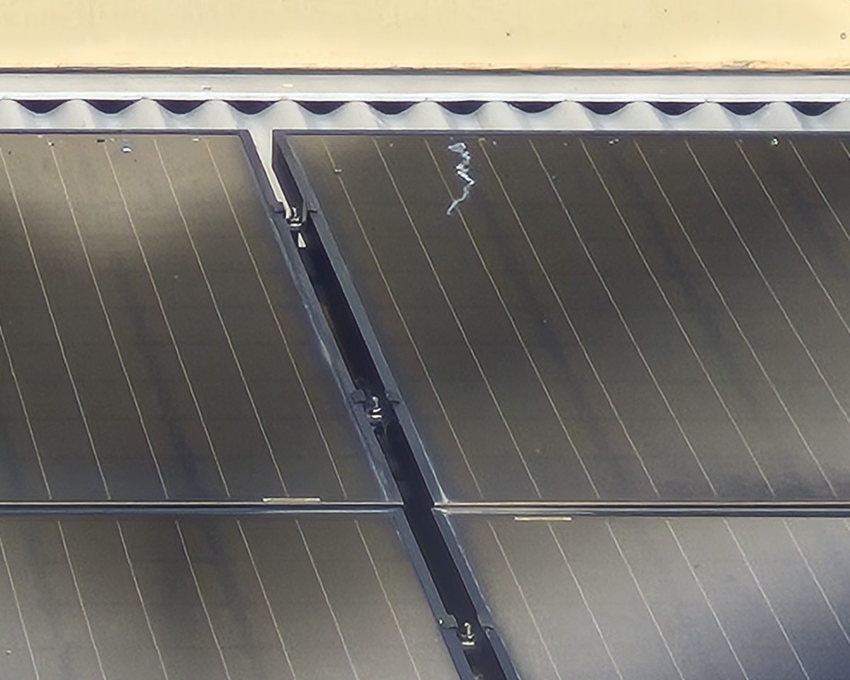 Close-up of a solar panel before cleaning, showing a bird dropping and a dull film of dust on the glass
